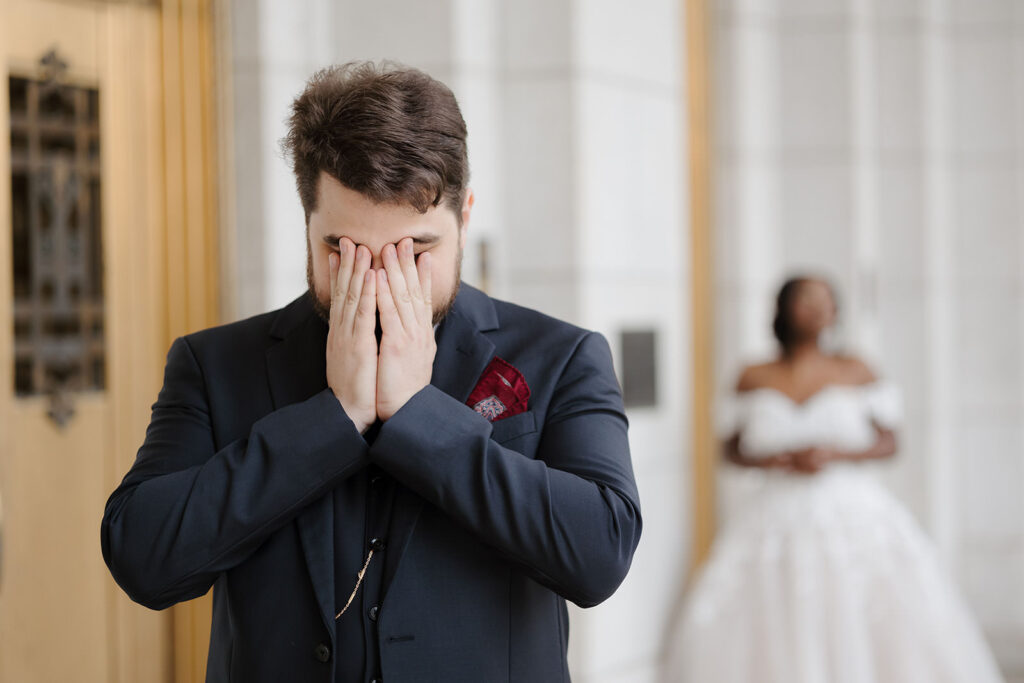 groom covering his face during first look in anticipation to see his bride